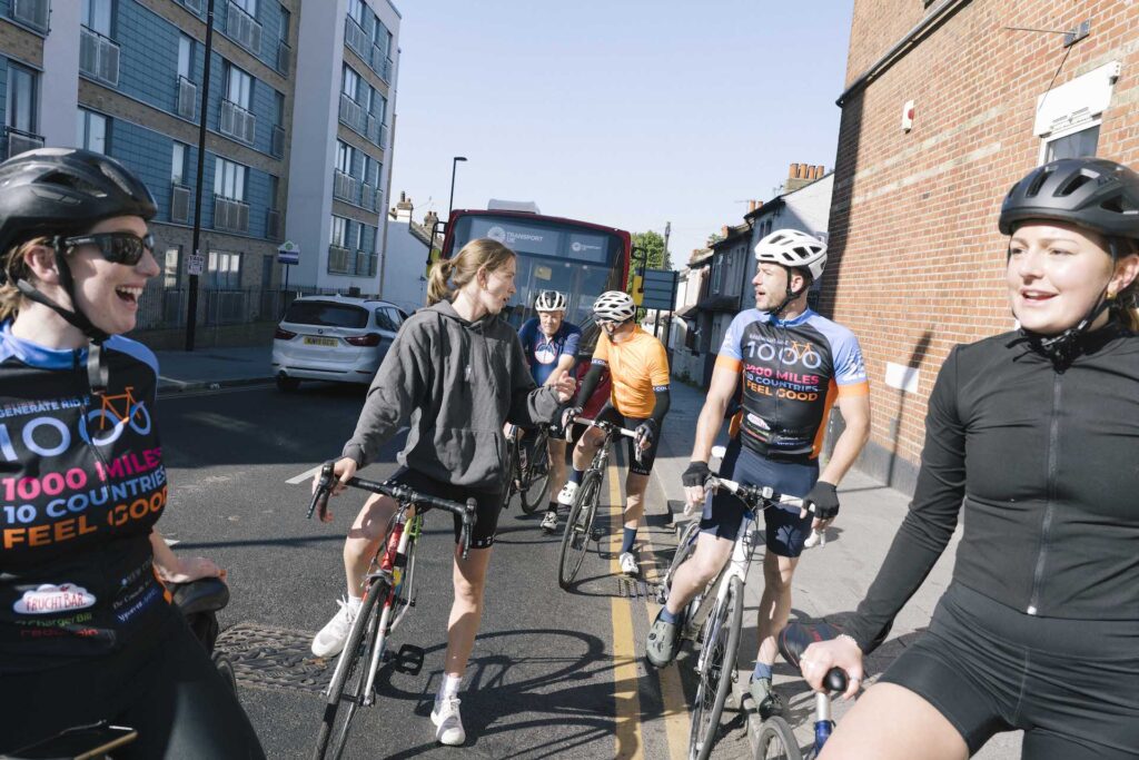 A group of Ride 1000 cyclists stopped at a traffic light, chatting and laughing