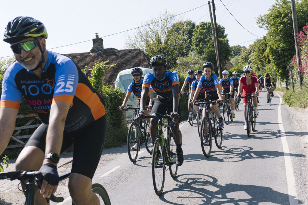 Ride 1000 cyclists riding down a country lane and smiling at the camera as they pass